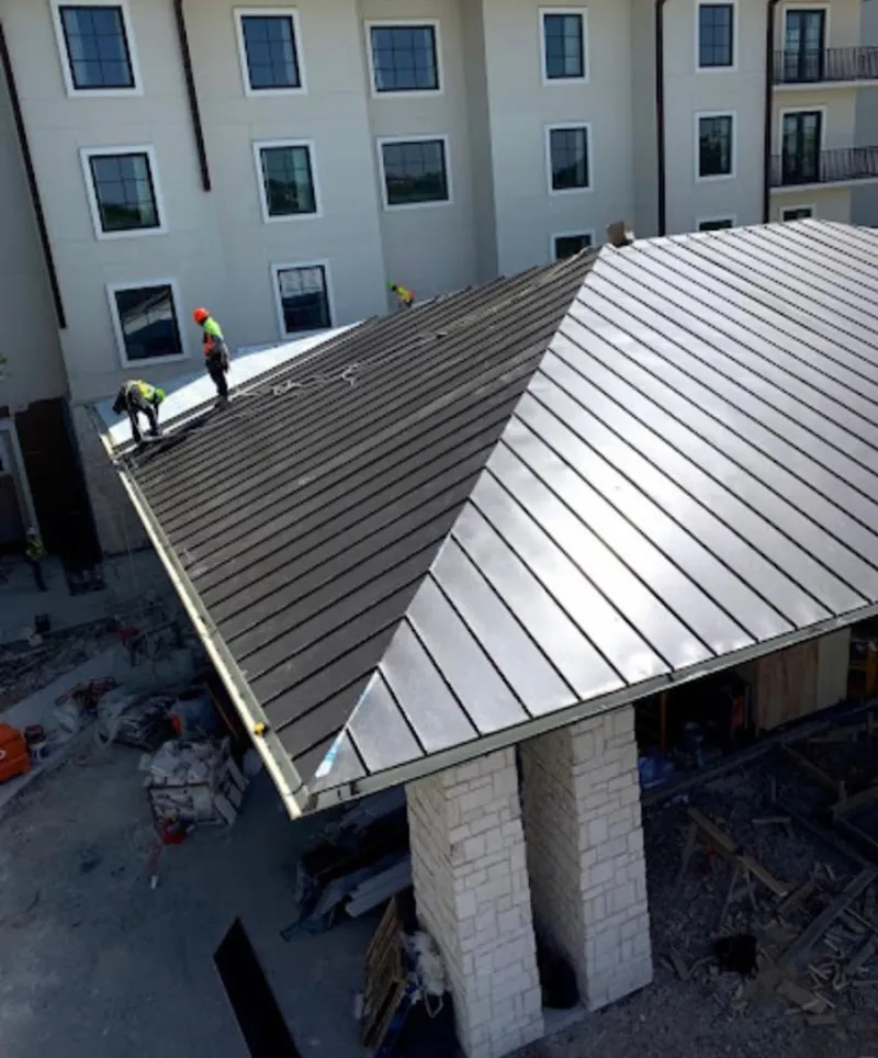 Crew installing standing seam metal roof panels on a commercial project in Mounds View